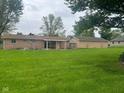 Spacious backyard view featuring a single-story brick home with a covered patio and a large, detached garage at 2026 S Q St, Elwood, IN 46036