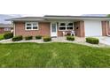 Charming brick home with well-maintained lawn and landscaping with outdoor chairs on the front porch at 2508 Pamela Ct, Anderson, IN 46012