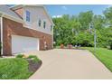 Side view of a brick and siding home featuring an extended driveway leading to a basketball hoop and spacious backyard at 3267 Cimmaron Ash Ct, Zionsville, IN 46077