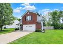Two-story home with brick facade, white garage door, and long driveway at 6809 Amber Springs Way, Indianapolis, IN 46237