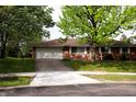 Brick home with a driveway and front lawn shaded by mature trees at 706 Bobs Ct, Beech Grove, IN 46107