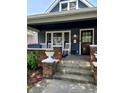 Inviting covered front porch with brick pillars, white rocking chairs, and blooming flower boxes at 1132 Evison St, Indianapolis, IN 46203