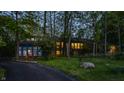 Serene wooded property showcasing an architecturally striking stone home with illuminated interiors for a warm and inviting feel at 12469 Springmill Rd, Carmel, IN 46032