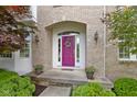 Inviting front entrance with a vibrant purple door, decorative wreath, and potted flowers at 14094 Pecos Ct, Carmel, IN 46033