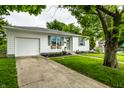 Quaint home with an attached garage, complemented by a green lawn and sidewalk at 1431 N Bolton Ave, Indianapolis, IN 46219