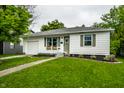 Inviting home with green lawn, complemented by a quaint front facade and attached garage at 1431 N Bolton Ave, Indianapolis, IN 46219