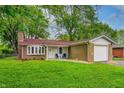 Charming brick home with a well-maintained lawn, brick chimney, and attached one car garage at 2228 Dover St, Anderson, IN 46013