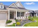 Cozy front porch with white chairs, perfect for relaxing, complemented by beautiful landscaping and a stone walkway at 3463 Sunnyvale Dr, Brownsburg, IN 46112