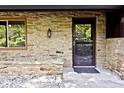 A cozy stone home entrance with a secure black screen door, window, and rustic lantern fixture at 6248 Graham Rd, Indianapolis, IN 46220
