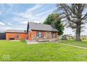 Attractive single-story home with orange siding, a stone chimney, a large front yard, and a fun playset at 671 W 350 N, Shelbyville, IN 46176