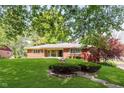 Charming single-story brick home with a well-manicured lawn and mature trees at 7135 Huntington Rd, Indianapolis, IN 46240