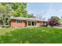 Charming single-story brick home with a well-manicured lawn and mature trees at 7135 Huntington Rd, Indianapolis, IN 46240