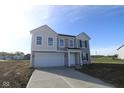 Charming two-story home with gray siding, white trim, an attached garage and a well-lit front porch at 7323 Waylon Way, Indianapolis, IN 46239
