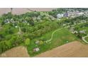 Aerial view of the parcel, featuring tree-lined boundaries and a road, with a backdrop of homes and agricultural fields at 8293 Water St, Coatesville, IN 46121