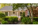 Beautiful front facade and porch area features brick and white paneling and manicured bushes and trees at 8770 N Pennsylvania St, Indianapolis, IN 46240
