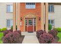 Close up view of condominium entrance with brick facade and neatly manicured shrubs at 8910 Hunters Creek Dr # 207, Indianapolis, IN 46227
