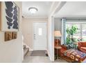 Bright foyer featuring a staircase, white door, and a glimpse into a cozy living room with comfortable seating at 9832 Scotch Pine Ln, Indianapolis, IN 46256