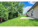 Spacious backyard with lush green grass, concrete patio, mature trees, and partial fencing at 10412 Cedar Dr, Fishers, IN 46037