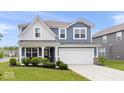 Charming two-story home with blue siding, white trim, covered porch, landscaped yard, and attached two-car garage at 10419 Pronghorn Ln, Indianapolis, IN 46239