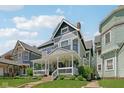 Attractive two-story gray home showcasing a inviting front porch with white railing and lush lawn at 1616 N Delaware St, Indianapolis, IN 46202