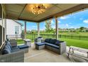 Covered patio boasts comfortable seating, a modern fire pit, and a view of the fenced backyard and neighborhood at 3592 Gillsland Rd, Bargersville, IN 46106