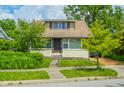 A cozy two-story home featuring classic architecture and inviting curb appeal with mature trees and landscaping at 4163 Otterbein Ave, Indianapolis, IN 46227