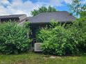 Backyard with overgrown bushes, air conditioner, and screened door at 4336 Abby Creek Ln, Indianapolis, IN 46205