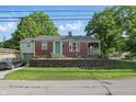 Charming brick home with a green door, garage, retaining wall, and well-manicured front yard at 6102 Primrose Ave, Indianapolis, IN 46220