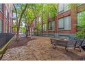 A cozy courtyard with bench seating offers a tranquil outdoor space amidst mature trees at 630 N College Ave # 105, Indianapolis, IN 46204