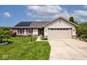Inviting single-story home featuring a well-maintained lawn, solar panels, and attached two-car garage at 6406 Longhorn Ct, Indianapolis, IN 46237