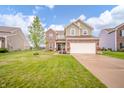 Charming two-story home with brick and siding exterior, a well-manicured lawn, and a driveway at 6579 Aster Dr, Pendleton, IN 46064