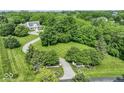 Stunning aerial view of a home on a sprawling lot with mature trees, a winding driveway, and lush landscaping at 7182 Hunt Club Dr, Zionsville, IN 46077