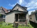 View of the back of the house with a covered porch and overgrown yard at 811 W 25Th St, Indianapolis, IN 46208