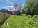 Fenced backyard with green lawn, trees and a view of neighboring buildings at 811 W 25Th St, Indianapolis, IN 46208