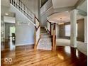 A grand foyer with hardwood floors and a staircase featuring white railings and wood trim at 12044 Bird Key Blvd, Fishers, IN 46037