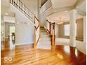 Stunning foyer with hardwood floors, a staircase, and decorative pillars leading to other living areas at 12044 Bird Key Blvd, Fishers, IN 46037