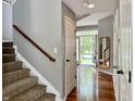 A bright hallway with hardwood floors, a staircase, and a view of the front yard through the open door at 12044 Bird Key Blvd, Fishers, IN 46037