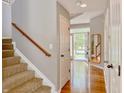 Hallway and staircase featuring wood floors, leading to the front door and upper level at 12044 Bird Key Blvd, Fishers, IN 46037