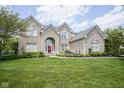 Attractive brick home featuring a manicured lawn and a striking red front door at 13244 Snow Owl Dr, Carmel, IN 46033