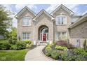 Beautiful brick home with a red front door, landscaped garden and a charming walkway at 13244 Snow Owl Dr, Carmel, IN 46033