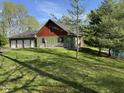 Exterior view of the home showcasing a three-car garage, lush lawn, and beautiful landscaping at 1340 Apache Trl, Martinsville, IN 46151