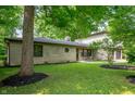 Beautiful side view of home with stone facade, mature trees, and manicured lawn at 2120 Wynnedale Rd, Indianapolis, IN 46228