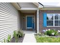 Inviting covered front porch with a bright blue door, beautiful plants, and brick detailing at 2717 Arklow Way, Brownsburg, IN 46112