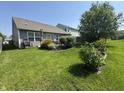 An open backyard with a small patio area, mature landscaping, and grass at 2911 W Hawanian Ln, Monrovia, IN 46157