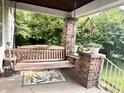 Relaxing front porch with a wooden porch swing and brick pillar creating an inviting outdoor space at 3745 Winthrop Ave, Indianapolis, IN 46205
