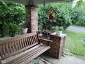 Inviting front porch with a swing and brick pillars adorned with plants and hanging flower decor at 3745 Winthrop Ave, Indianapolis, IN 46205