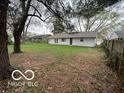 Large, grassy backyard with a white single-story home in the background, surrounded by trees at 4108 Steinmetz Dr, Indianapolis, IN 46254