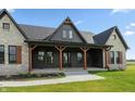 Up close exterior showcasing stone, dark siding, and a covered front porch with wood columns at 4457 E County Road 850 N, Pittsboro, IN 46167