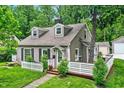 Charming two-story home with a brick foundation, neutral siding and a white picket fence, surrounded by lush greenery at 5104 Carvel Ave, Indianapolis, IN 46205