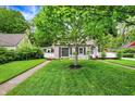 Charming two-story home with a well-manicured lawn, mature trees, and a welcoming walkway leading to the front door at 5104 Carvel Ave, Indianapolis, IN 46205